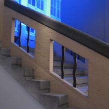 Treppe mit Lichtinstallation. Die Stufen gehen unter dem gemauerten Geländer weiter
